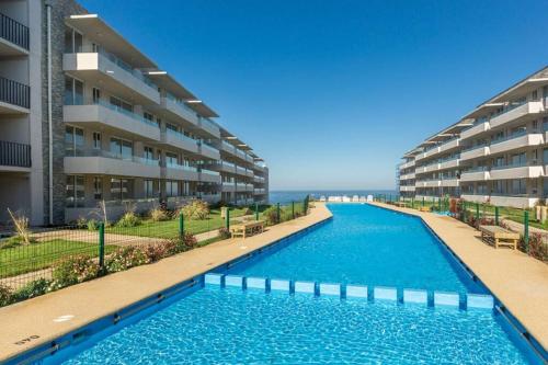 a swimming pool in front of a apartment building at Hermoso Departamento familiar en condominio in El Tabo