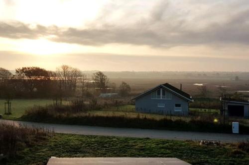 uma casa ao lado de um campo com o pôr do sol em Kranichhöhe em Hohwacht