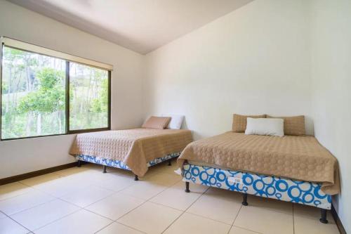 1 dormitorio con 2 camas y ventana en Rancho Bellavista, unique views, pool & wifi, en Turrialba