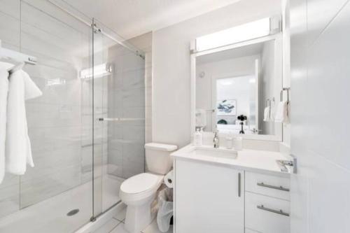 La salle de bains blanche est pourvue d'une douche et de toilettes. dans l'établissement ✦Chic Haven✦3BR Near DT & WEM, King Bed, Trails, Fast Wifi, Sleeps 6!, à Edmonton