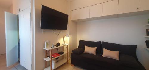 a living room with a black couch and a flat screen tv at Palermo Panoramic in Buenos Aires