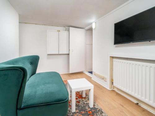a living room with a green couch and a tv at "FurnishedRentals Direct" WiggenHouse Stylish 3 Bedroom house Sleeps 8 with Free Parking, 2 Bathrooms, near to Watford High Street and Watford Football Stadium, Suitable for visiting Harry Potter Warner Bros Studio and London in Watford