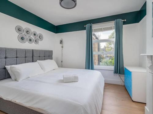 une chambre avec un grand lit blanc et une fenêtre dans l'établissement "FurnishedRentals Direct" WiggenHouse Stylish 3 Bedroom house Sleeps 8 with Free Parking, 2 Bathrooms, near to Watford High Street and Watford Football Stadium, Suitable for visiting Harry Potter Warner Bros Studio and London, à Watford