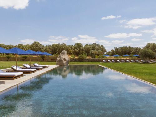 a swimming pool with lounge chairs and blue umbrellas at São Lourenço do Barrocal in Monsaraz