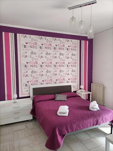 una camera da letto con un letto viola e due asciugamani di Butterfly House a Castellammare di Stabia