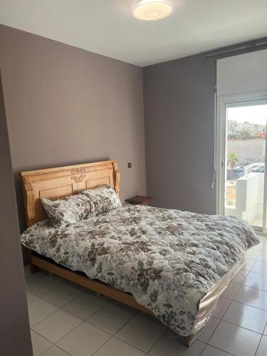 een slaapkamer met een bed met een dekbed en een raam bij Agadir Dreamhouse in Agadir