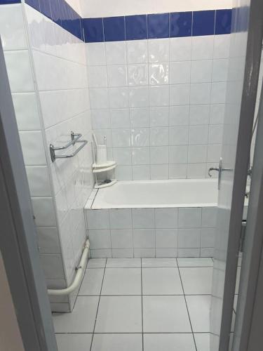 a white tiled bathroom with a tub and a toilet at Agadir Dreamhouse in Agadir