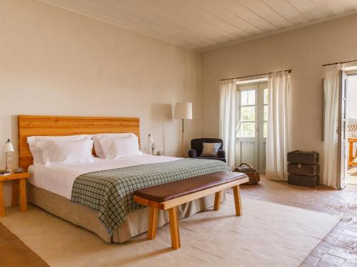 um quarto com uma cama, uma cadeira e janelas em São Lourenço do Barrocal em Monsaraz