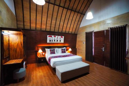 a bedroom with a large bed and a bench in it at Adil Villa & Resort in Ubud
