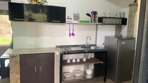 a kitchen with a sink and a stove and a refrigerator at Moderna cabaña en medio de la naturaleza in Santandercito
