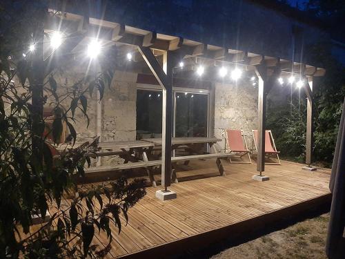 una terraza de madera con una mesa de picnic y luces en Domaine de la Brette en Condom