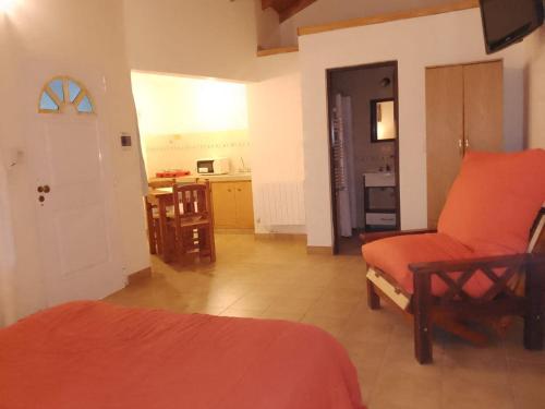 Zimmer mit einem Bett und einem Stuhl sowie einer Küche in der Unterkunft Cabañas Los Cardales in Chascomús