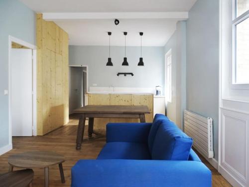 salon z niebieską kanapą i stołem w obiekcie Au cœur de Trouville. Appartement de 3 pièces. w mieście Trouville-sur-Mer