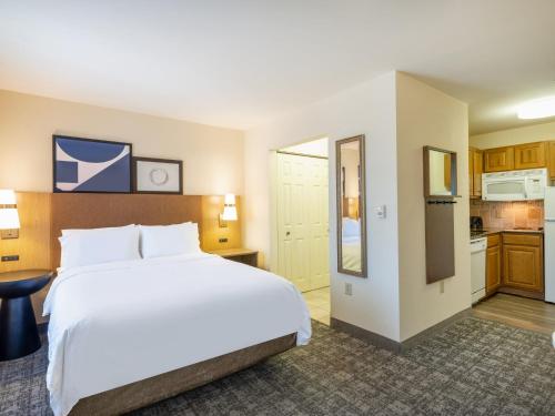 a bedroom with a large bed and a kitchen at Staybridge Suites Milwaukee Airport South by IHG in Franklin