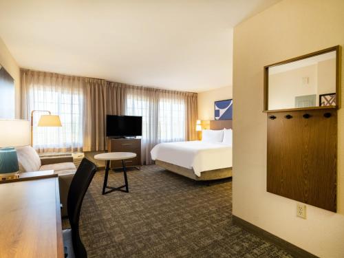 a hotel room with a bed and a living room at Staybridge Suites Milwaukee Airport South by IHG in Franklin