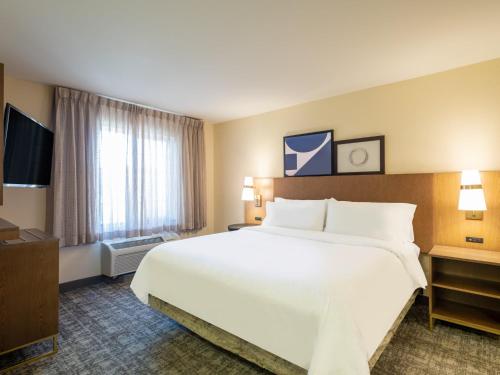 a hotel room with a large white bed and a window at Staybridge Suites Milwaukee Airport South by IHG in Franklin