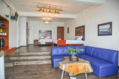 a living room with a blue couch and a bed at Seven Blue House Village & Lodge in Bacalar