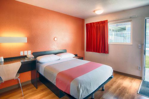 a bedroom with a bed and a desk and a red window at Motel 6-Mammoth Lakes, CA in Mammoth Lakes