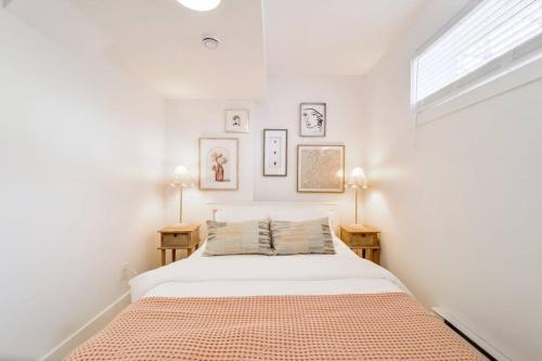 a white bedroom with a bed and two lamps at The Nook & Cranny Bsmt Suite, Near WEM & DT, Fast WiFi! Sleeps 4 in Edmonton