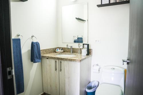 W łazience znajduje się umywalka, lustro i toaleta. w obiekcie Avitat Joy City &Volcano View 2Brm Pool &Gym w mieście San Salvador