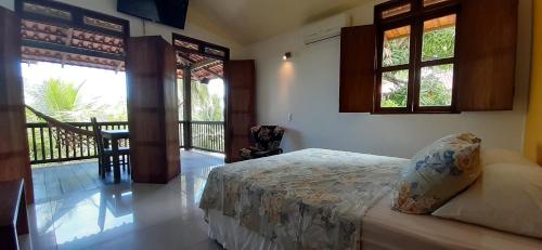 a bedroom with a bed and a balcony with windows at Ecolodge Batel Alagoas in Coruripe