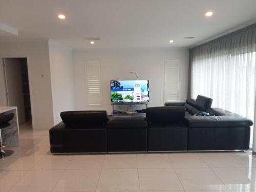 a living room with a couch and a flat screen tv at Luxurious entire family home in Mooroopna