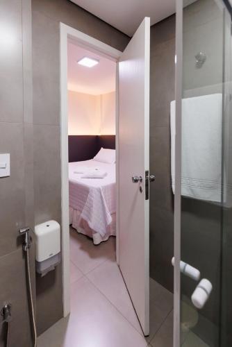 a room with a bed and a door to a bathroom at Tonello Business Hotel in Campo Mourão
