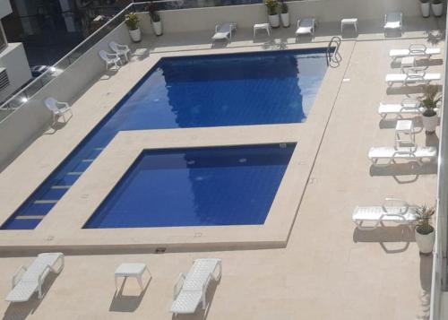 - une grande piscine avec des tables et des chaises blanches dans l'établissement Apto Nacaela-Bocagrande cerca a la playa, à Carthagène des Indes