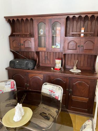 a wooden cabinet with a glass table and chairs at Casa de Tati en Cosquín Córdoba in Cosquín