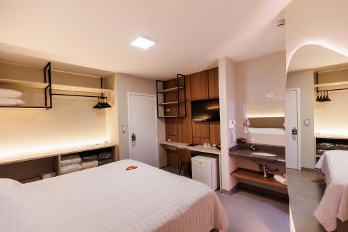a bedroom with a white bed and a sink at Tonello Business Hotel in Campo Mourão