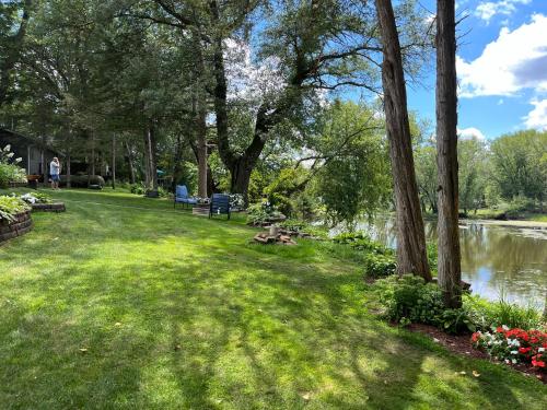a park with a river and trees and grass and flowers at Breezeway Bay - Waterfront Full House in Wisconsin Dells