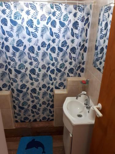 a bathroom with a sink and a blue and white shower curtain at alquilerpordiviedma in Viedma