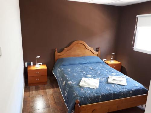 1 dormitorio con 1 cama con sábanas azules y 2 mesitas de noche en alquilerpordiviedma en Viedma