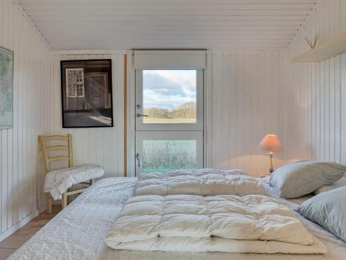 a white bedroom with a large bed and a window at 5 person holiday home in Læsø in Læsø