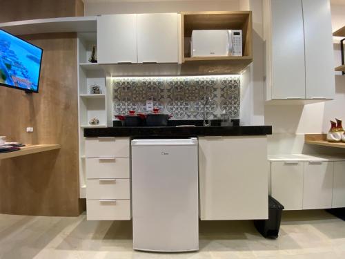 a kitchen with white cabinets and a counter top at Recanto Novo Premium Flat in Cabo Frio