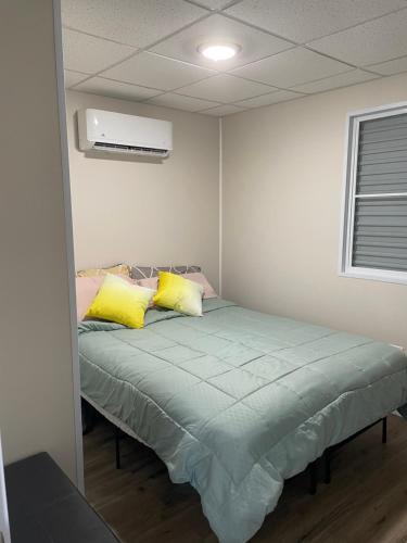 a bedroom with a bed with yellow and pink pillows at Casitas at Flambohio Beach Camp in Sabana