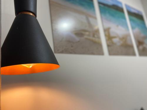 a black lamp with an orange shade next to a wall at Recanto Novo Premium Flat in Cabo Frio