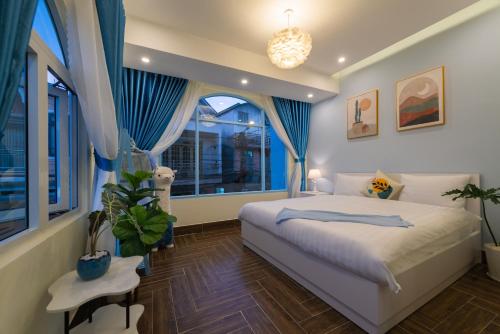 1 dormitorio con 1 cama con cortinas azules y ventana en Moc Thach Blue House DaLat, en Da Lat