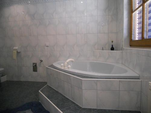 eine weiße Badewanne im Bad mit Fenster in der Unterkunft Ferienwohnungen/Holiday Apartments Lederer in Reisach