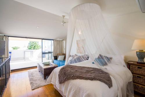 Schlafzimmer mit einem Bett mit Moskitonetz in der Unterkunft West End Warehousebathers Beachrooftop Balcony in Fremantle