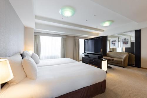 a hotel room with a large bed and a television at ANA Crowne Plaza Toyama by IHG in Toyama