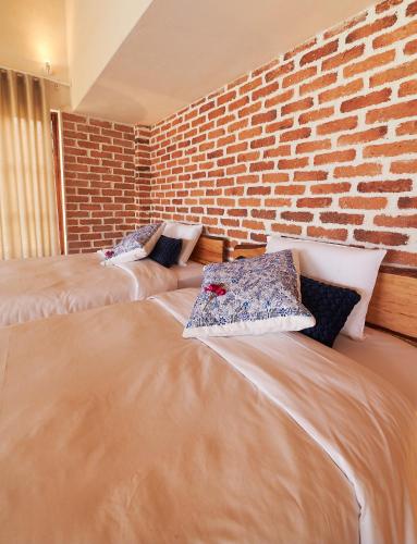 two beds in a room with a brick wall at Wayarumi Skyhotel in Carhuaz