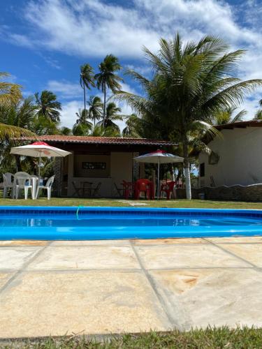 a swimming pool in front of a house with palm trees at Pousada Do Vozinho in Touros