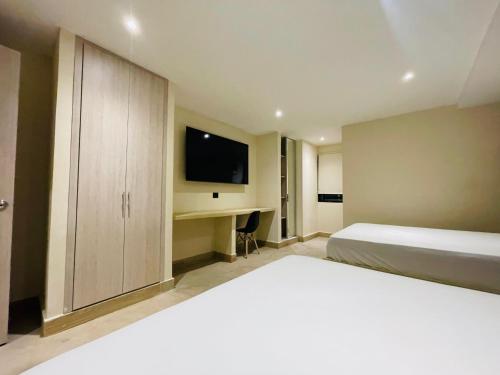 The Host at Santa Marta في سانتا مارتا: غرفة نوم بها سرير ومكتب مع تلفزيون