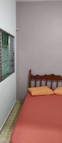 a bedroom with a bed with a red blanket and a window at SUÍTE - R&P - Centro in Peruíbe