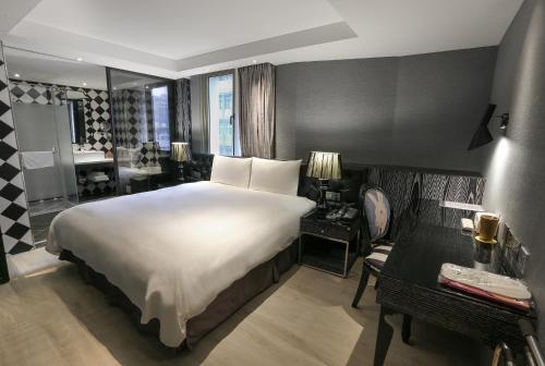 a bedroom with a large white bed and a bathroom at CHECK inn Taipei Main Station in Taipei
