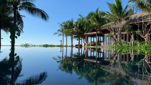 a house on the water with palm trees at The Anam Mui Ne in Mui Ne