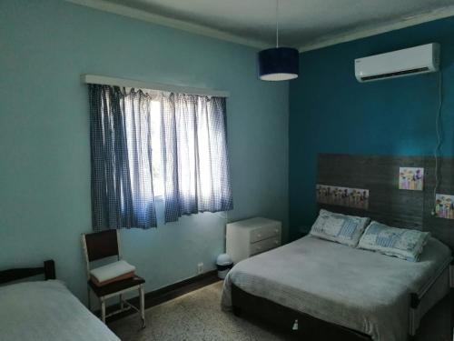 1 dormitorio con 2 camas, ventana y silla en Casa del Mar, en Montevideo