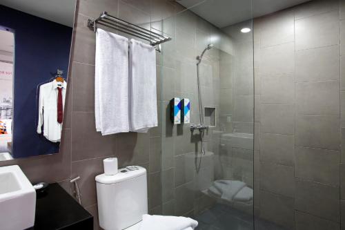 a bathroom with a toilet and a glass shower at Berry Biz Hotel Sunset Road in Seminyak