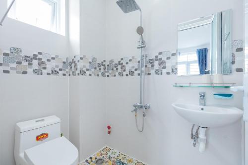 a white bathroom with a toilet and a sink at Villa Vũng Tàu - An Thảo Home's in Vung Tau